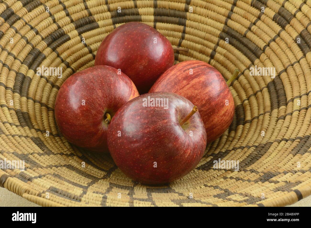 Pommes rouges fraîches délicieuses fruits dans un panier circulaire marron tissé Banque D'Images