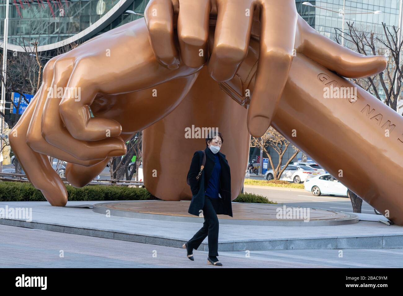 Séoul, Corée du Sud. 20 mars 2020. Une femme portant un masque de protection par mesure de précaution contre l'éclosion de marches de Coronavirus au-delà de la statue de Gangnam style.la Corée du Sud enregistre 131 morts et 9241 cas confirmés du nouveau coronavirus (COVID19) depuis que le pays a confirmé son premier cas le 21 janvier. Le gouvernement sud-coréen a fermé des écoles, annulé des événements et recommande la fermeture d'établissements religieux, sportifs et de vie nocturne. Crédit: Simon Shin/SOPA Images/ZUMA Wire/Alay Live News Banque D'Images