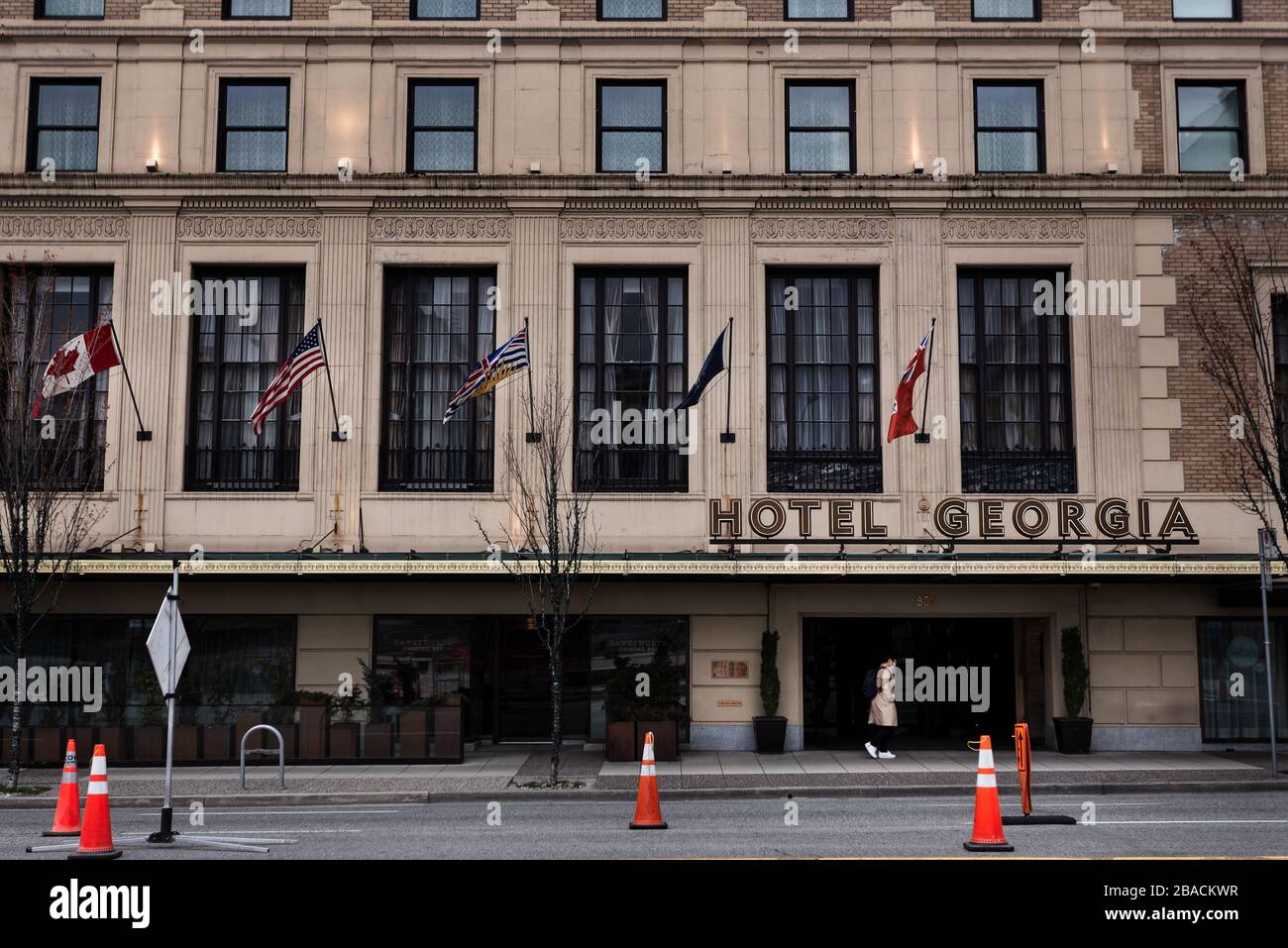 CENTRE-VILLE DE VANCOUVER, C.-B., CANADA - 23 MARS 2020: Une personne qui marche devant l'hôtel Georgia avec un facemask médical sur pendant la COVID-19 Banque D'Images
