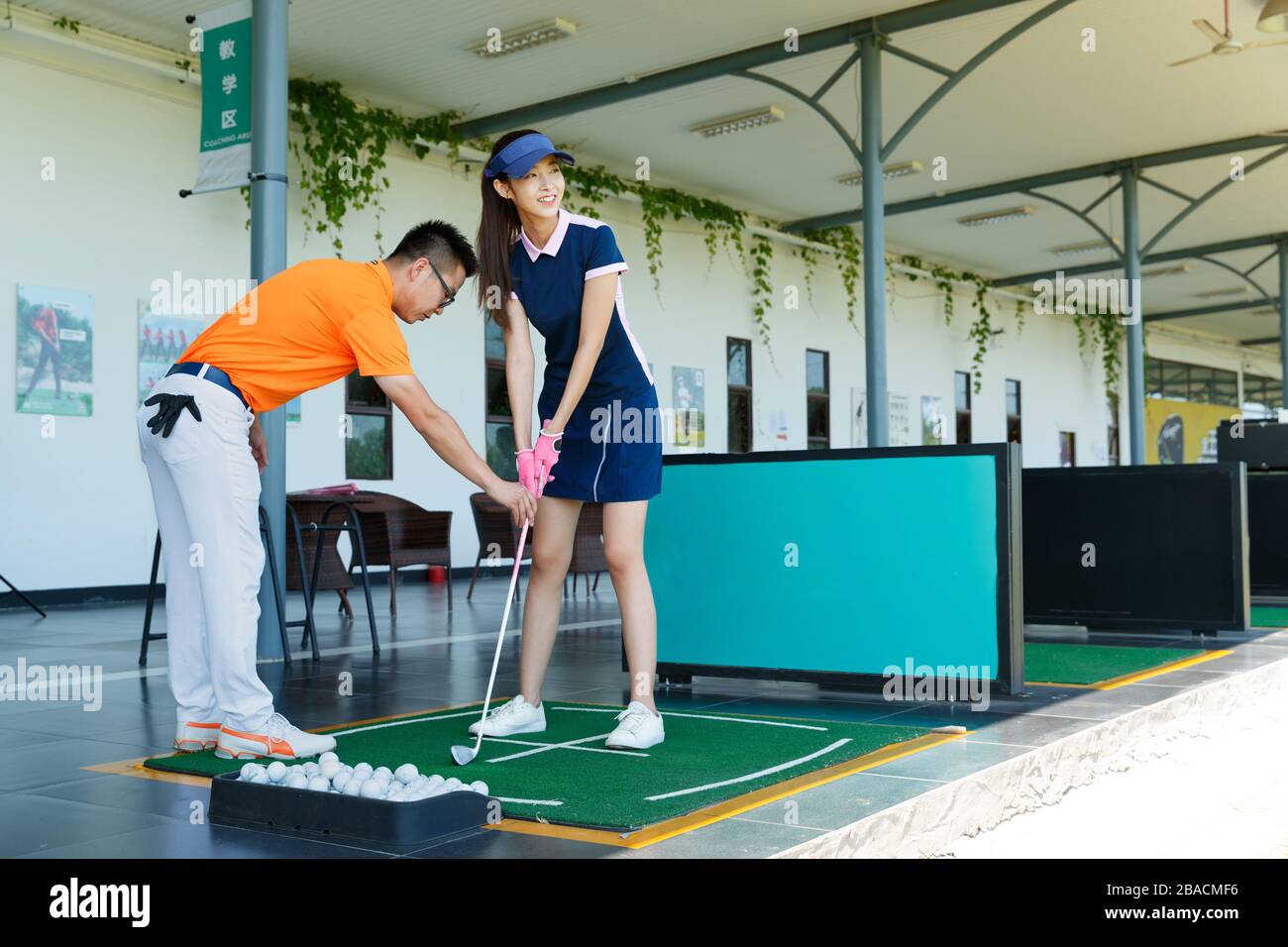 Le champ de pratique de l'entraînement de la jeune femme pour jouer au golf Banque D'Images