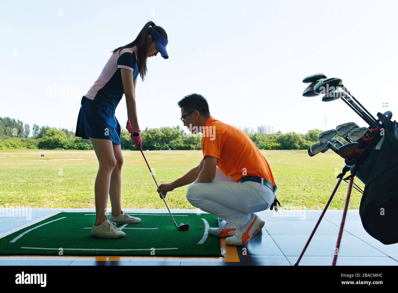 Le champ de pratique de l'entraînement de la jeune femme pour jouer au golf Banque D'Images