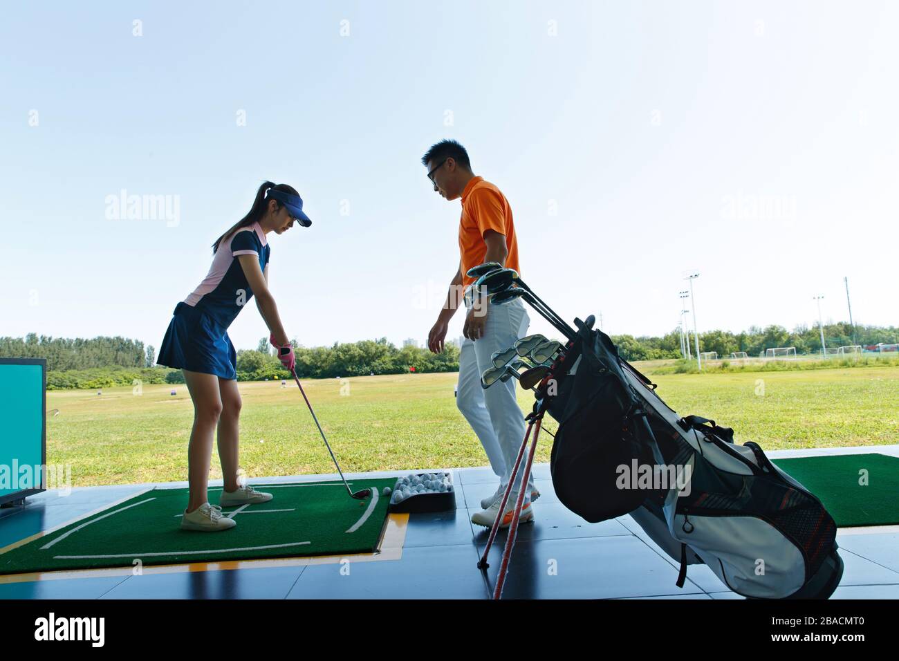 Le champ de pratique de l'entraînement de la jeune femme pour jouer au golf Banque D'Images