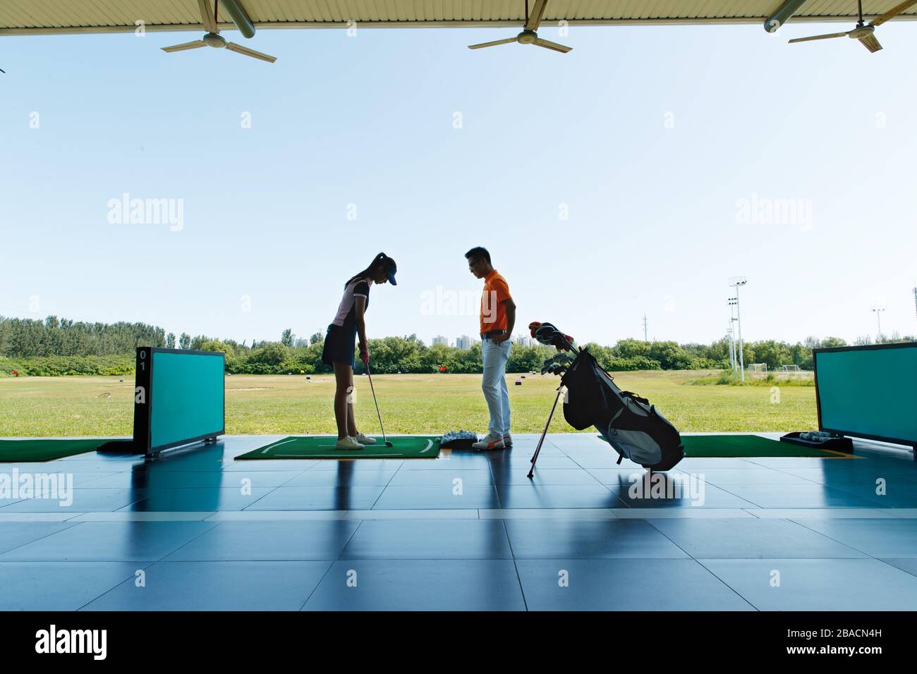 Le champ de pratique de l'entraînement de la jeune femme pour jouer au golf Banque D'Images