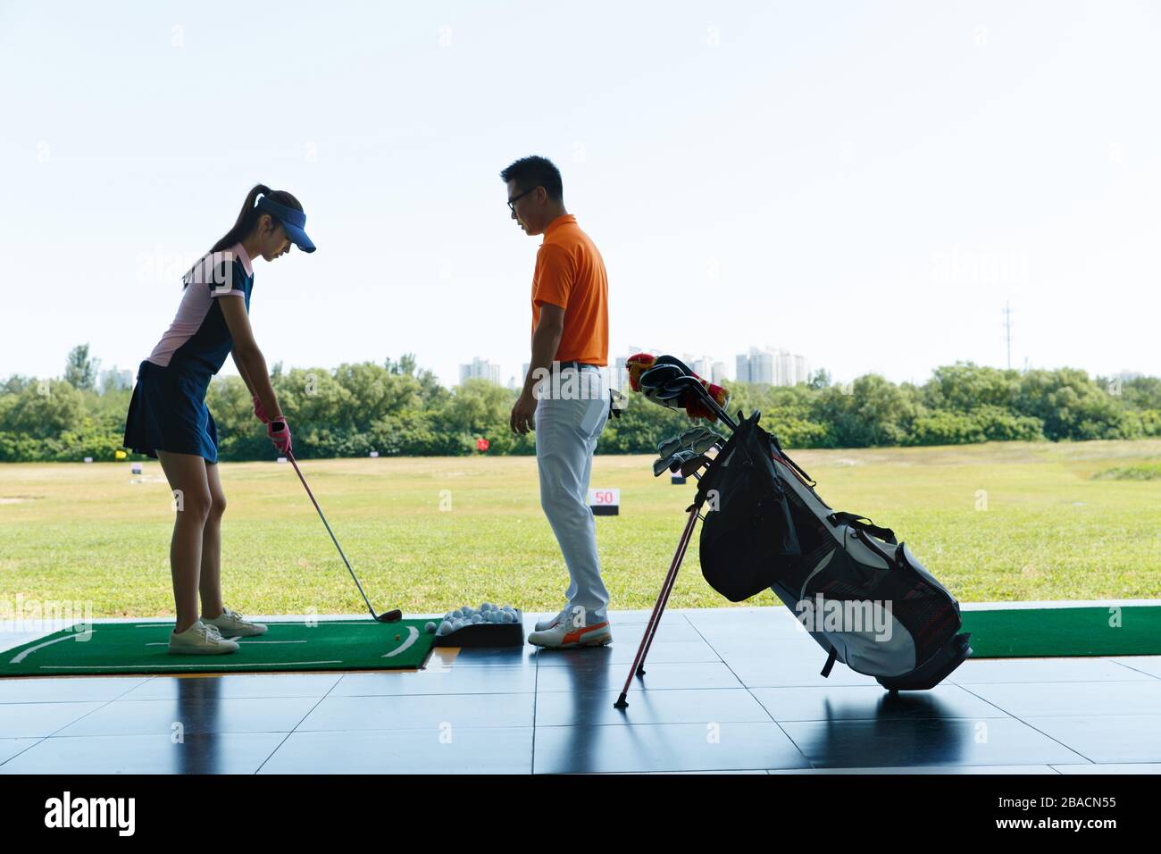 Le champ de pratique de l'entraînement de la jeune femme pour jouer au golf Banque D'Images