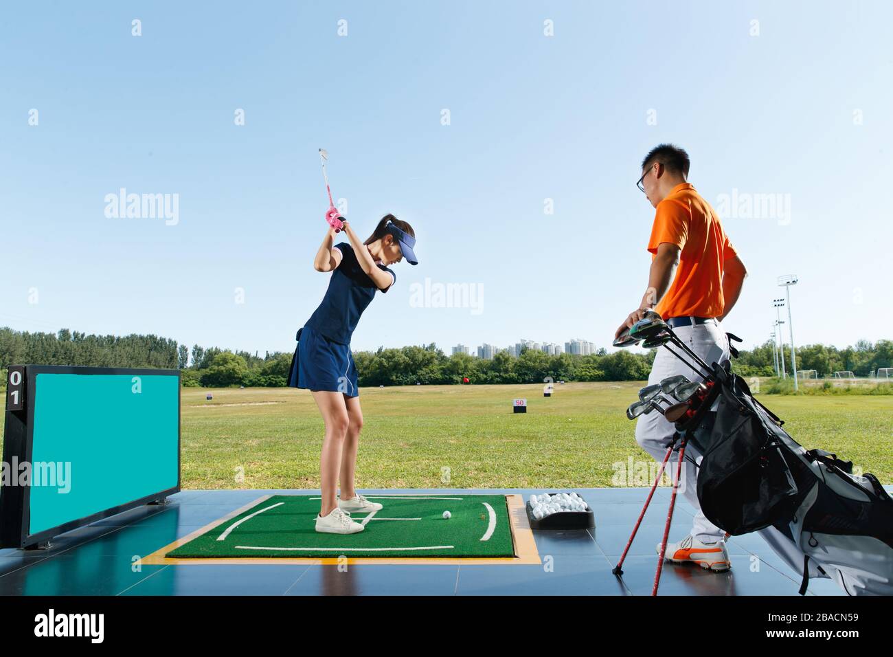 Le champ de pratique de l'entraînement de la jeune femme pour jouer au golf Banque D'Images