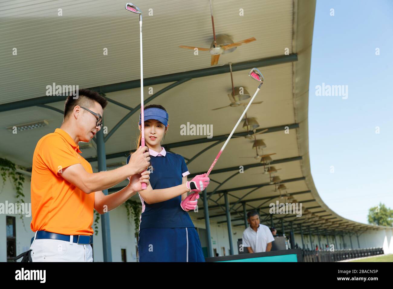 Le champ de pratique de l'entraînement de la jeune femme pour jouer au golf Banque D'Images