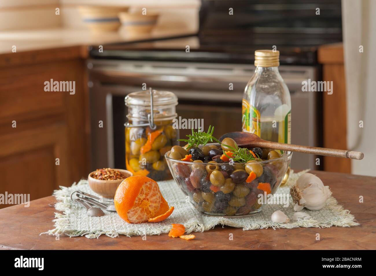 Préparation d'olives noires et vertes marinées à l'huile d'olive avec épices dans la cuisine. Banque D'Images