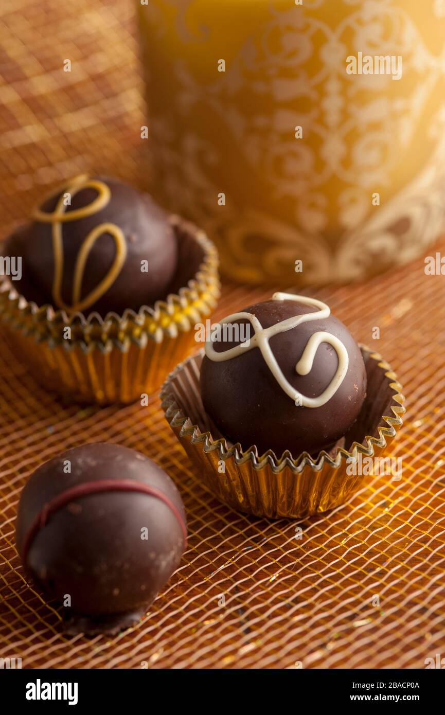 Truffes au chocolat noir en tasses d'or avec fond doré tourné dans le studio. Banque D'Images