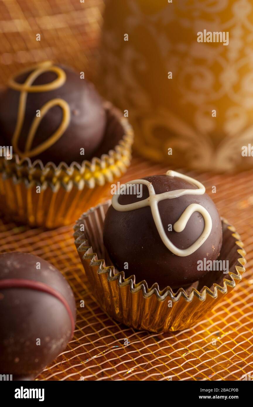 Truffes au chocolat noir en tasses d'or avec fond doré tourné dans le studio. Banque D'Images