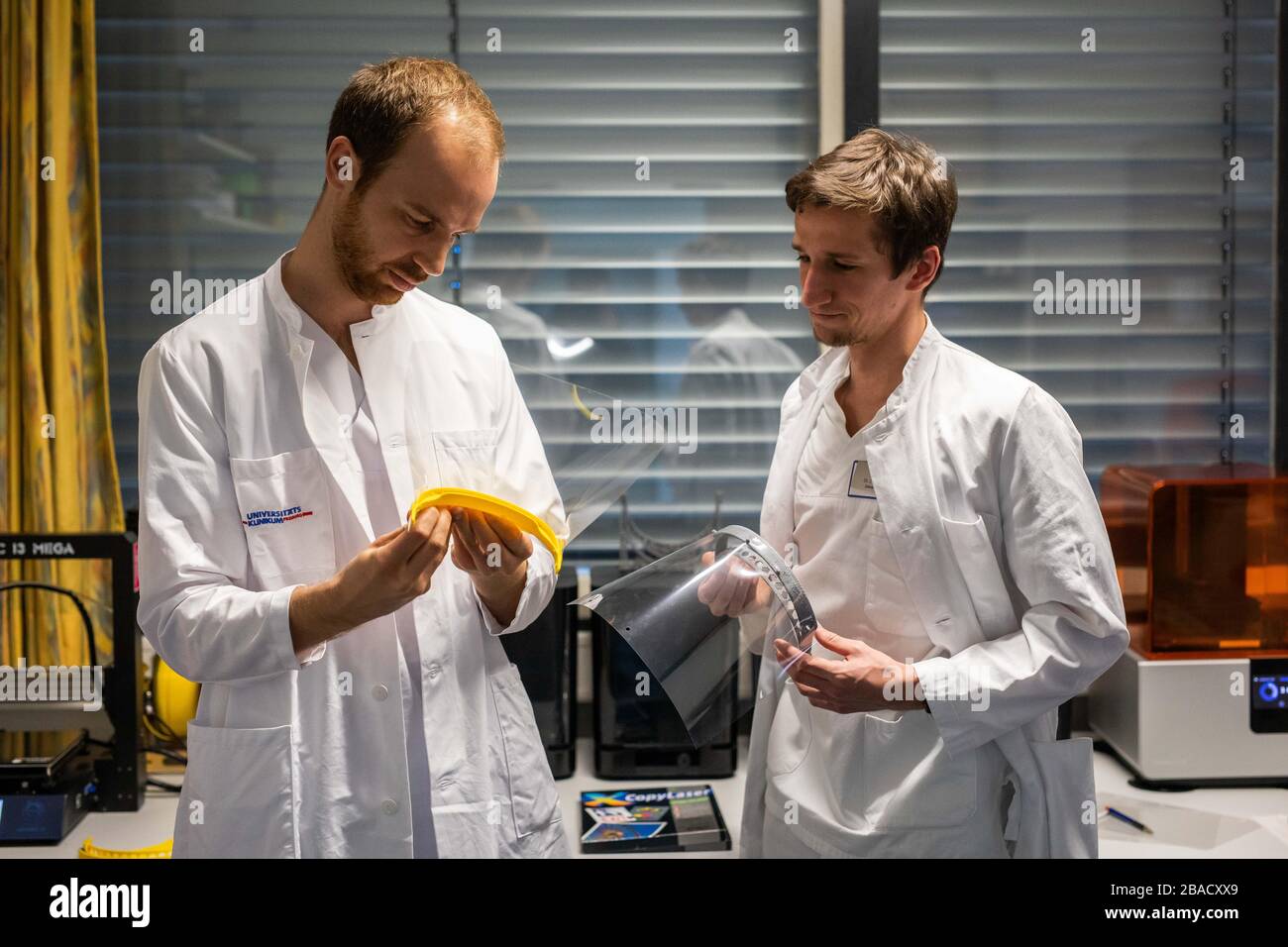 Fribourg, Allemagne. 26 mars 2020. Le professeur Benedikt Spies (l) et le Dr Julian Nold (r) détiennent chacun un masque de l'imprimante en trois dimensions dans leurs mains. L'hôpital universitaire de Fribourg fabrique actuellement ses propres supports qui peuvent être utilisés comme protection faciale en combinaison avec un film standard. Crédit: Philipp von Ditfurth/dpa/Alay Live News Banque D'Images