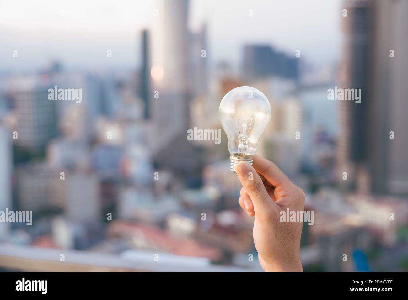 Coucher du soleil au-dessus de l'ampoule ampoule maisons urbaines. lampe transparent sur l'énergie solaire en milieu urbain, la cité, la ville de la vie nocturne. Symbole, concept de busi Banque D'Images