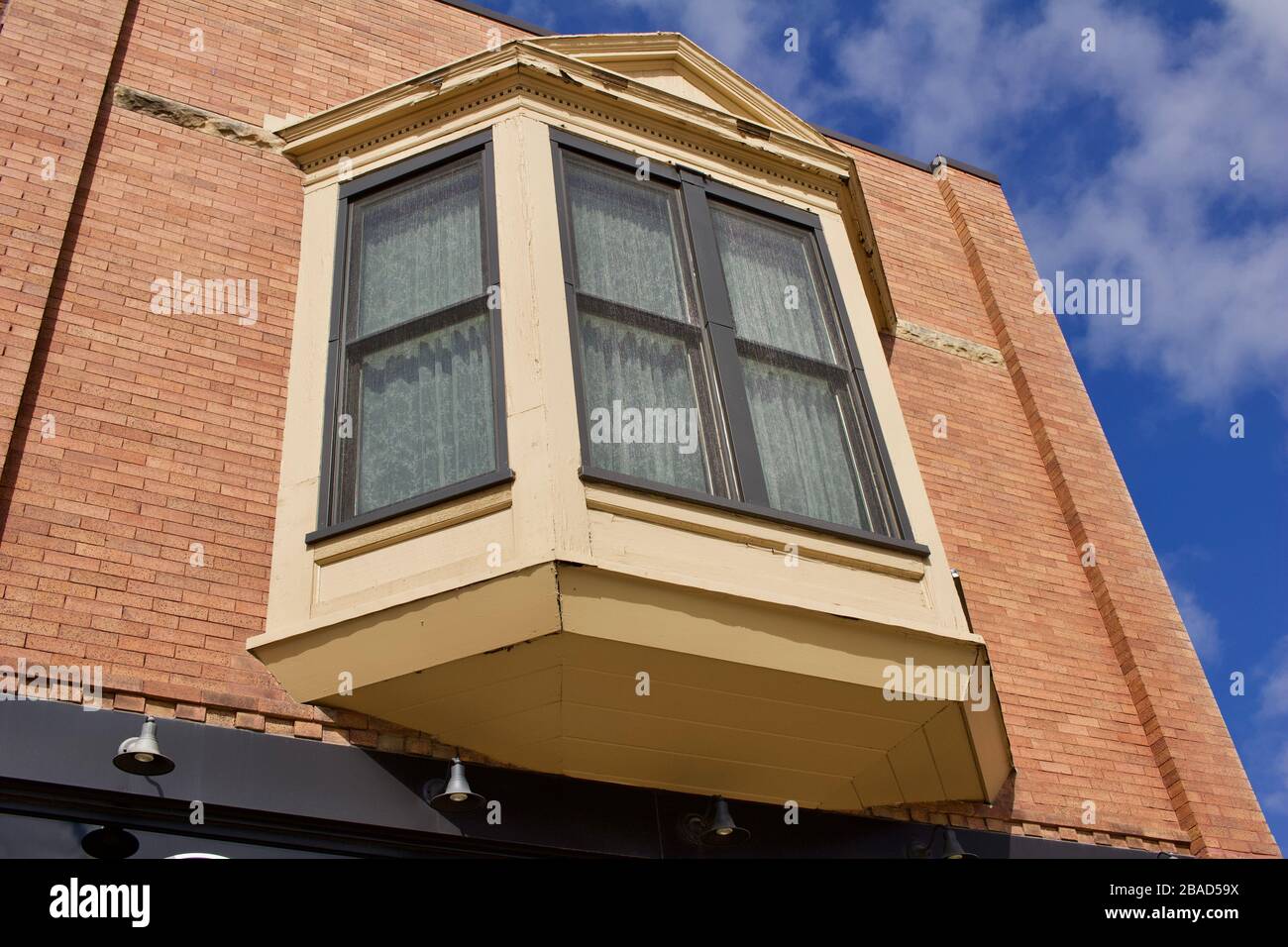 Vue vers le haut d'une texture de bâtiment en briques vintage brun clair avec une grande baie vitrée et un fond bleu ciel Banque D'Images