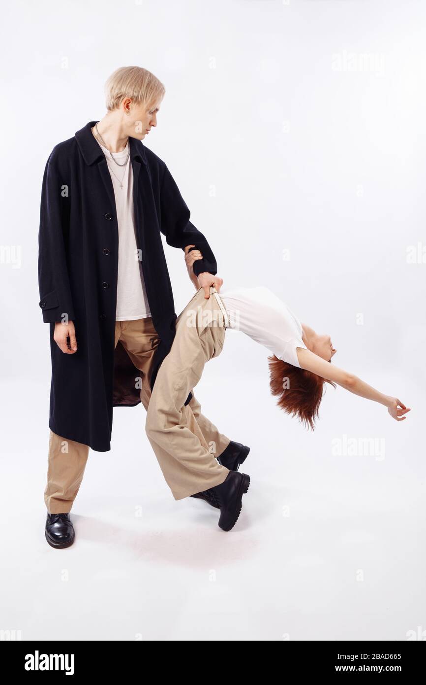 Un homme grand attire une fille à sa ceinture. La fille est reculée. Sur l'homme se trouve un manteau noir et un T-shirt blanc. Banque D'Images