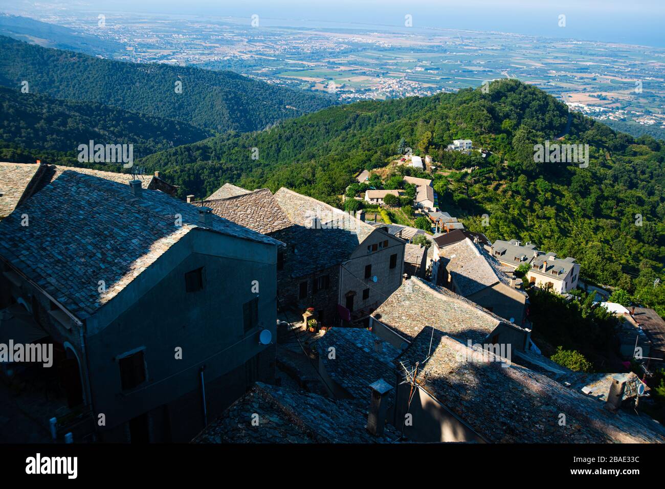 Vue en grand angle sur un village corsican dans les montagnes avec forêt et mer en arrière-plan Banque D'Images