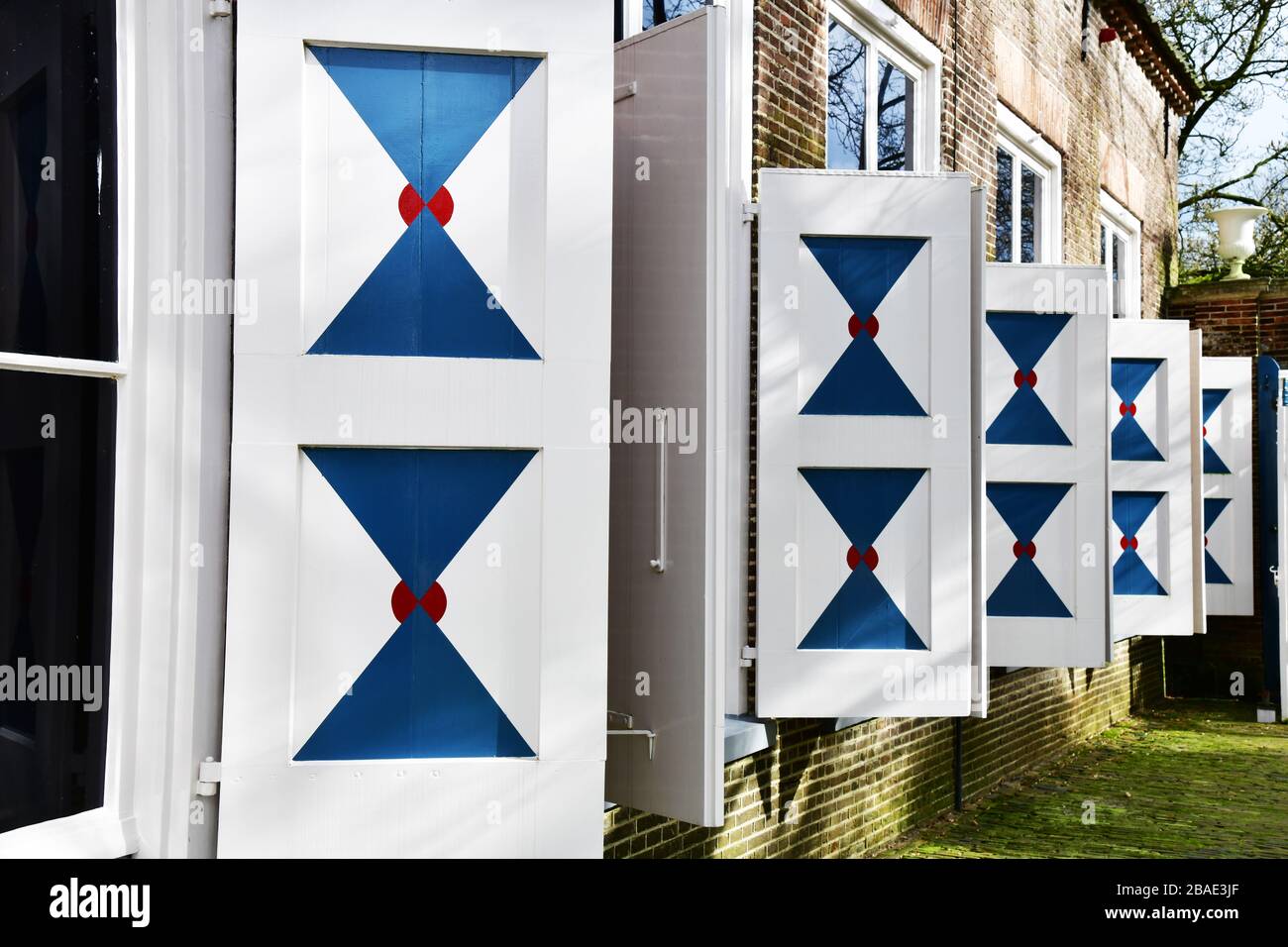 Vue latérale inclinée d'un grand nombre soigneusement doublé de volets extérieurs bleu et blanc lumineux de l'un des bâtiments du château de Nijenhuis. Banque D'Images