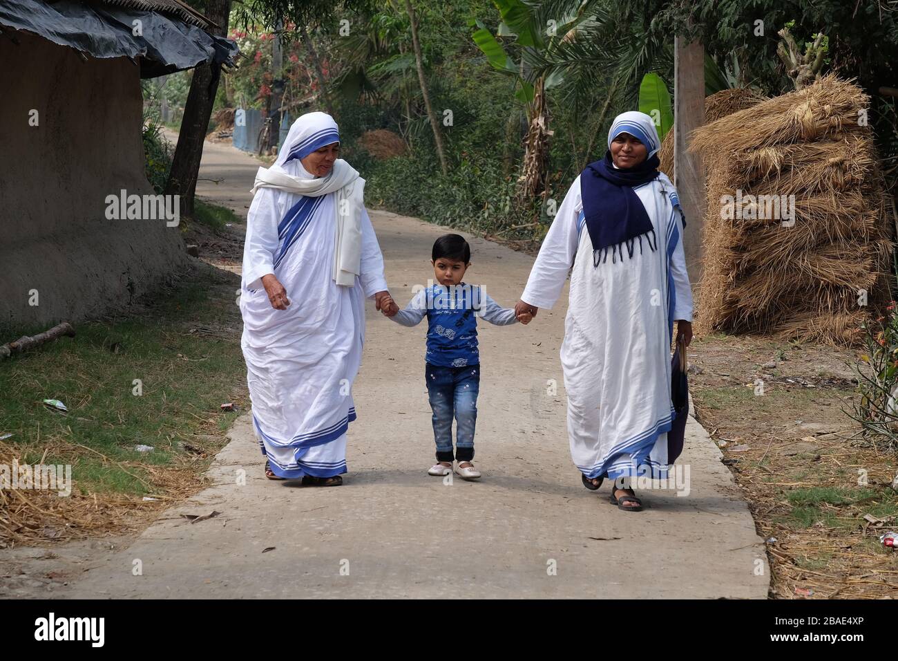 Missionnaires de la Charité - mère Teresa religieuses marchent avec l'enfant à Chunakhali, Bengale Ouest, Inde Banque D'Images