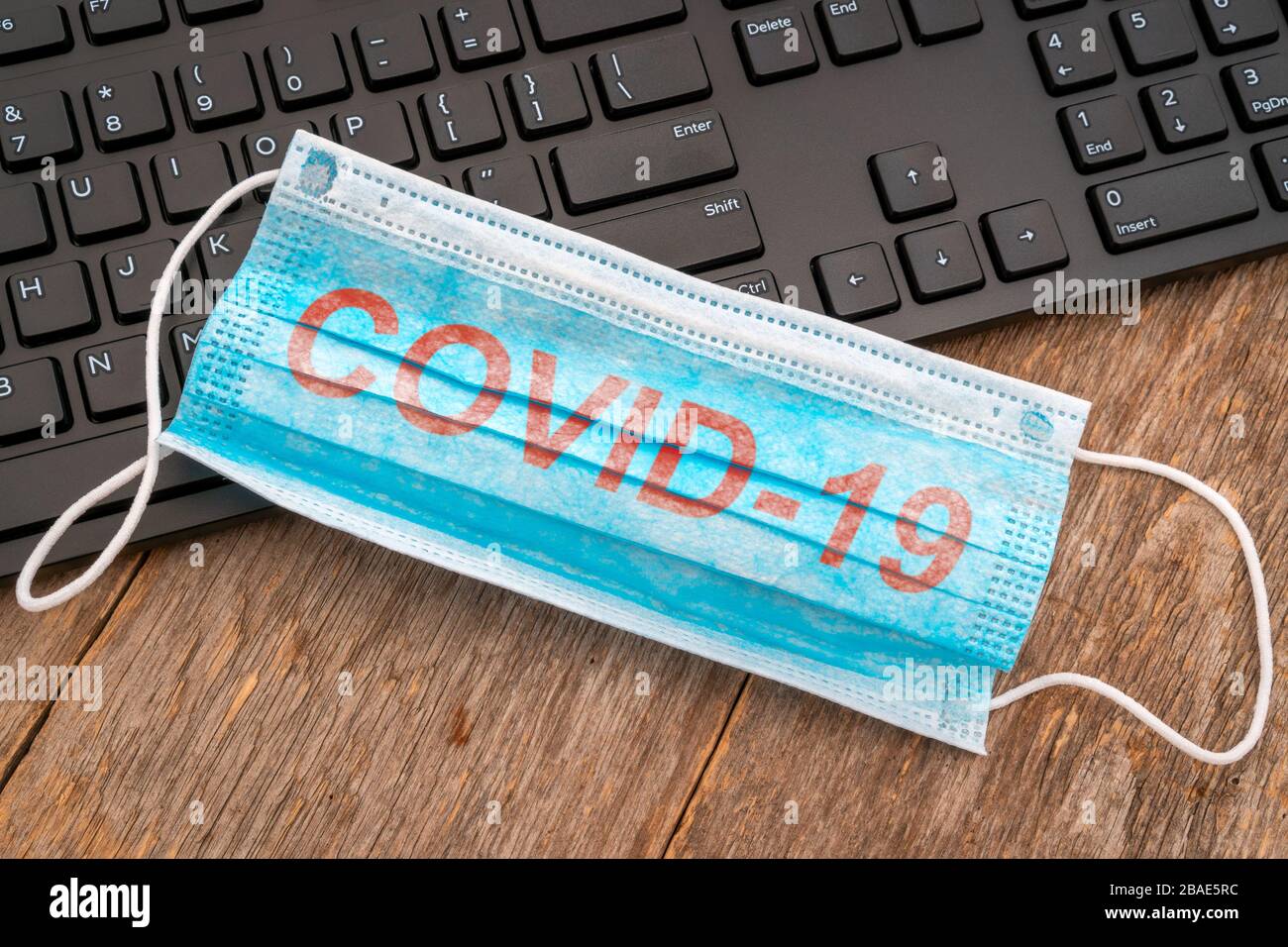 Le masque chirurgical est placé sur le clavier de l'ordinateur. Illustration pour protéger les employés de bureau qui travaillent dans le cas d'une épidémie de virus ou d'une pandémie. Banque D'Images