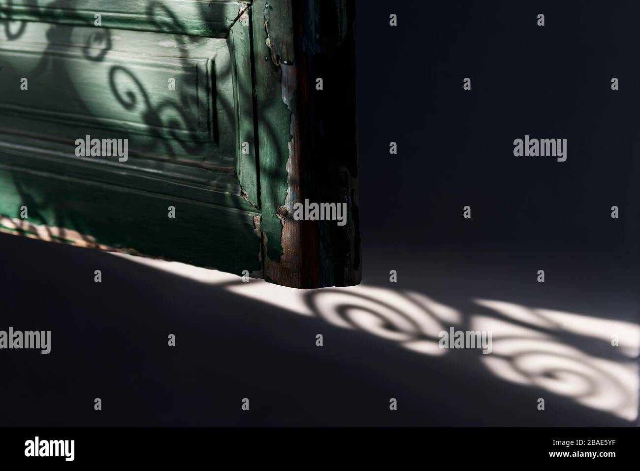 Ancienne fenêtre en bois (aveugle) avec ombres de grille marocaines. Image d'arrière-plan sombre. Banque D'Images