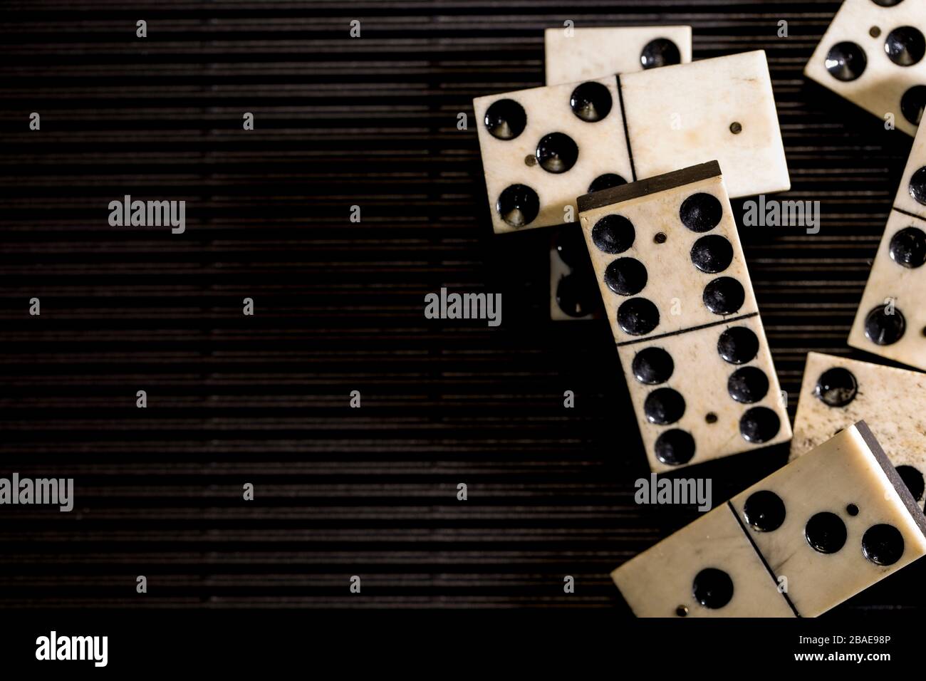 Domino comme concept abstrait. Magnifique domino ancien sur fond de papier noir. Banque D'Images