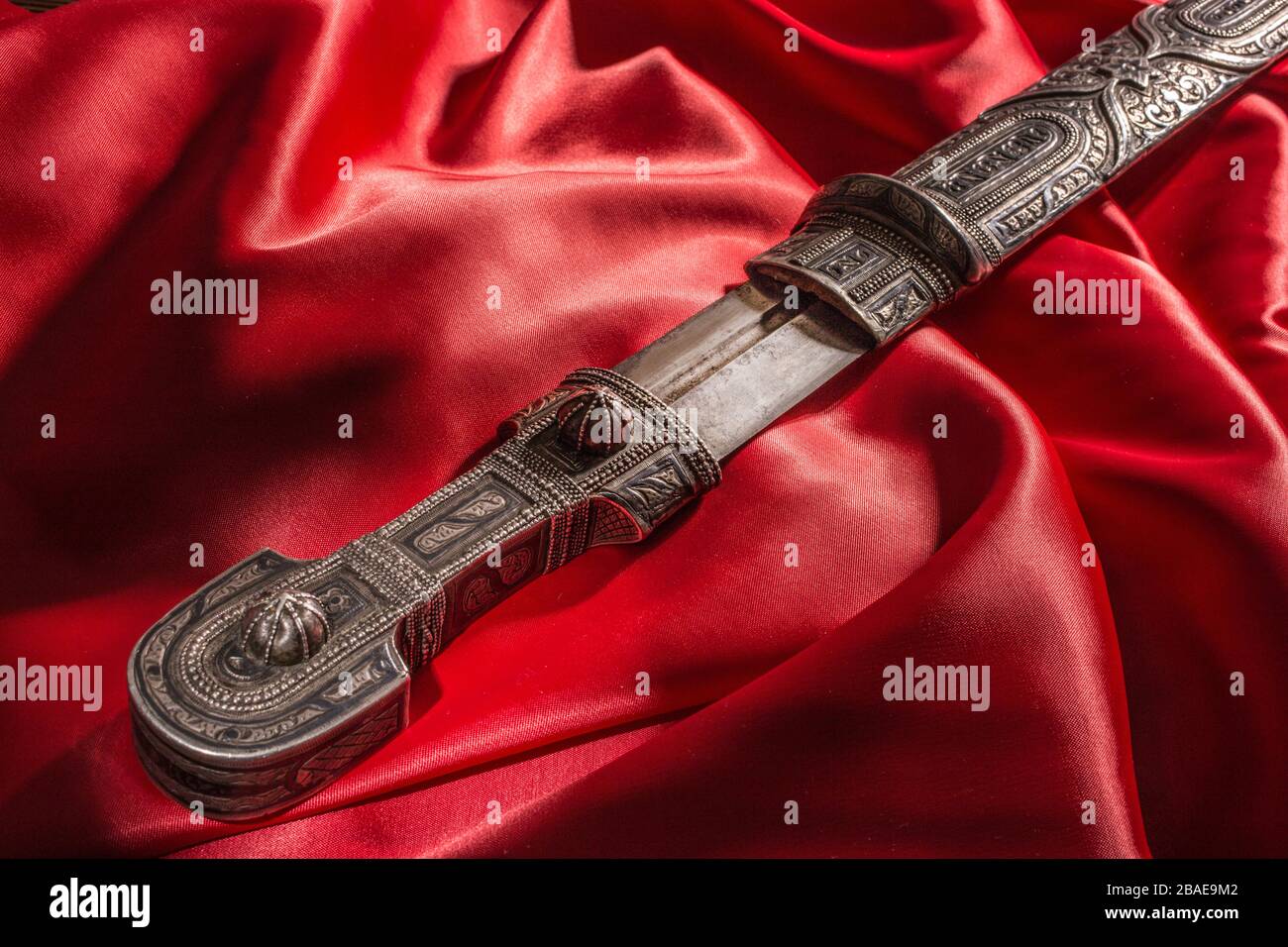 Bel exemple de dagger caucasien avec lame sous forme d'épée de Rome sur fond de soie rouge. XIXe siècle (époque des guerres russo-caucasiennes (1816-1864) Banque D'Images