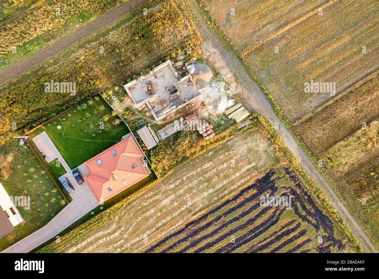 Vue aérienne de deux maisons privées, l'une en construction avec des murs en béton et en briques et l'autre avec un toit en tuiles rouges. Banque D'Images