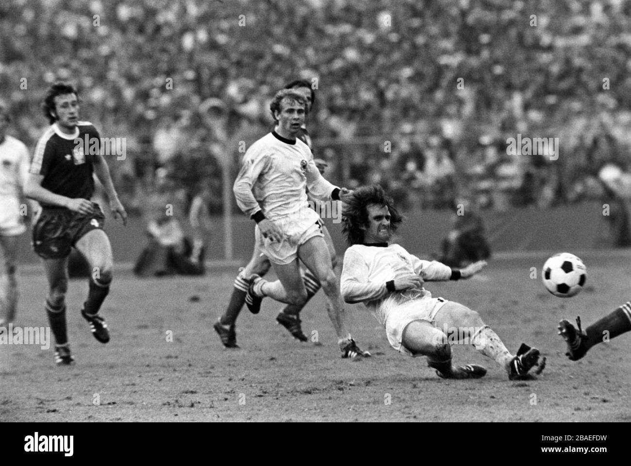 l-r Anton Szymanowski (Pologne) et Bernd Holzenbein (Allemagne de l'Ouest) regardent Wolfgang Overath (Allemagne de l'Ouest) à droite, se ferment Banque D'Images