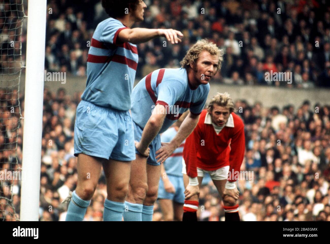 Bobby Moore de West Ham United (c) et Denis Law de Manchester United (r) prennent un reniflard alors qu'ils attendent un coin à prendre Banque D'Images