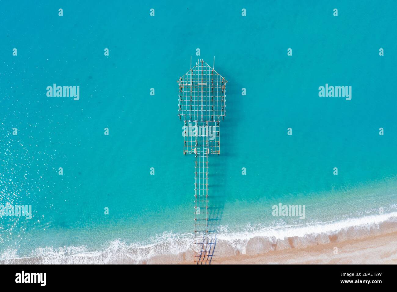 Vue aérienne sur les vagues de mer turquoise et la plage de sable et un quai en construction, Turquie, Antalya Banque D'Images