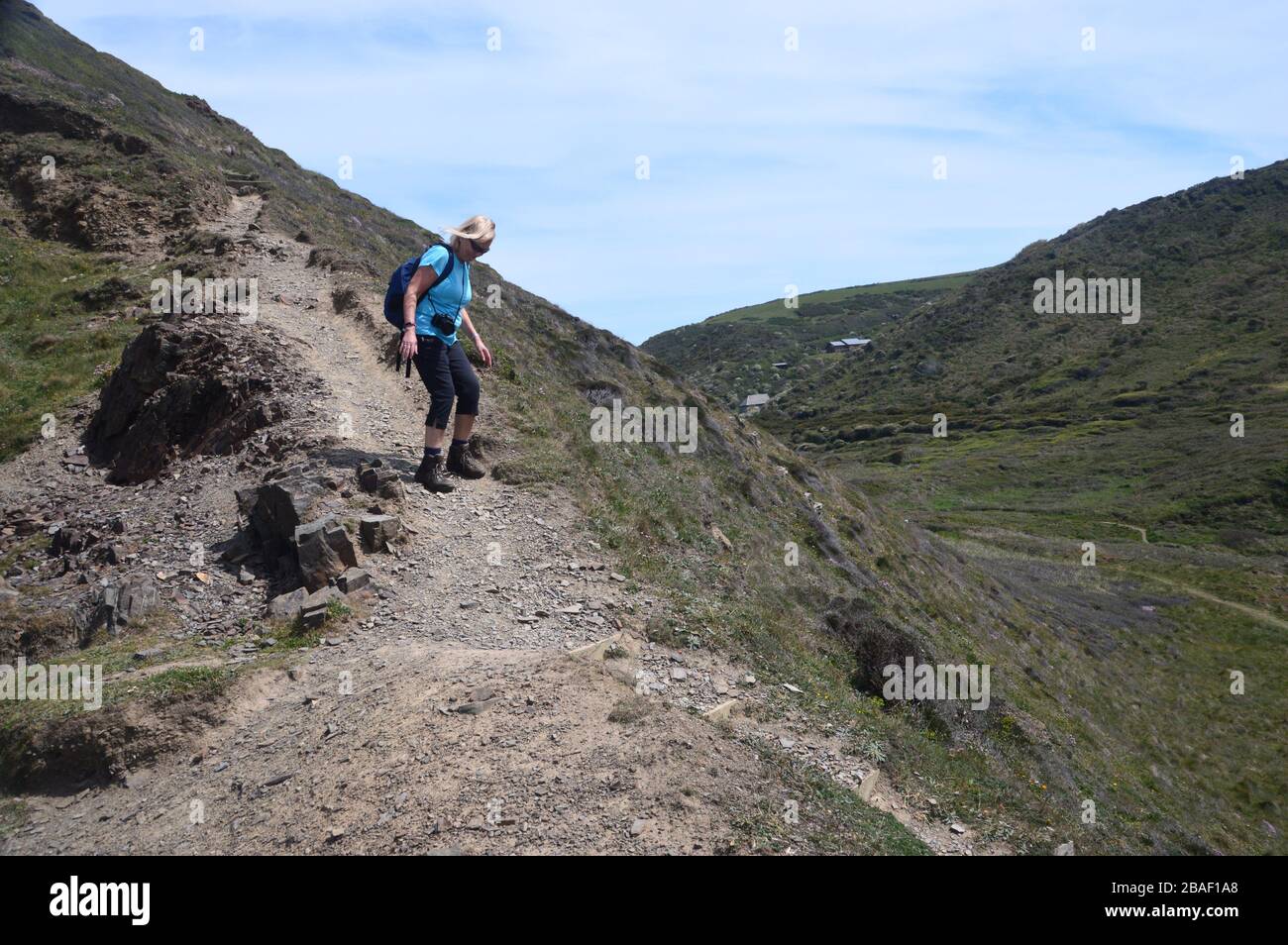 Lone Woman Hiker marchant sur une voie érodée abrupte vers la bouche de Welcombe sur le sentier côtier du sud-ouest, North Devon, Angleterre, Royaume-Uni Banque D'Images