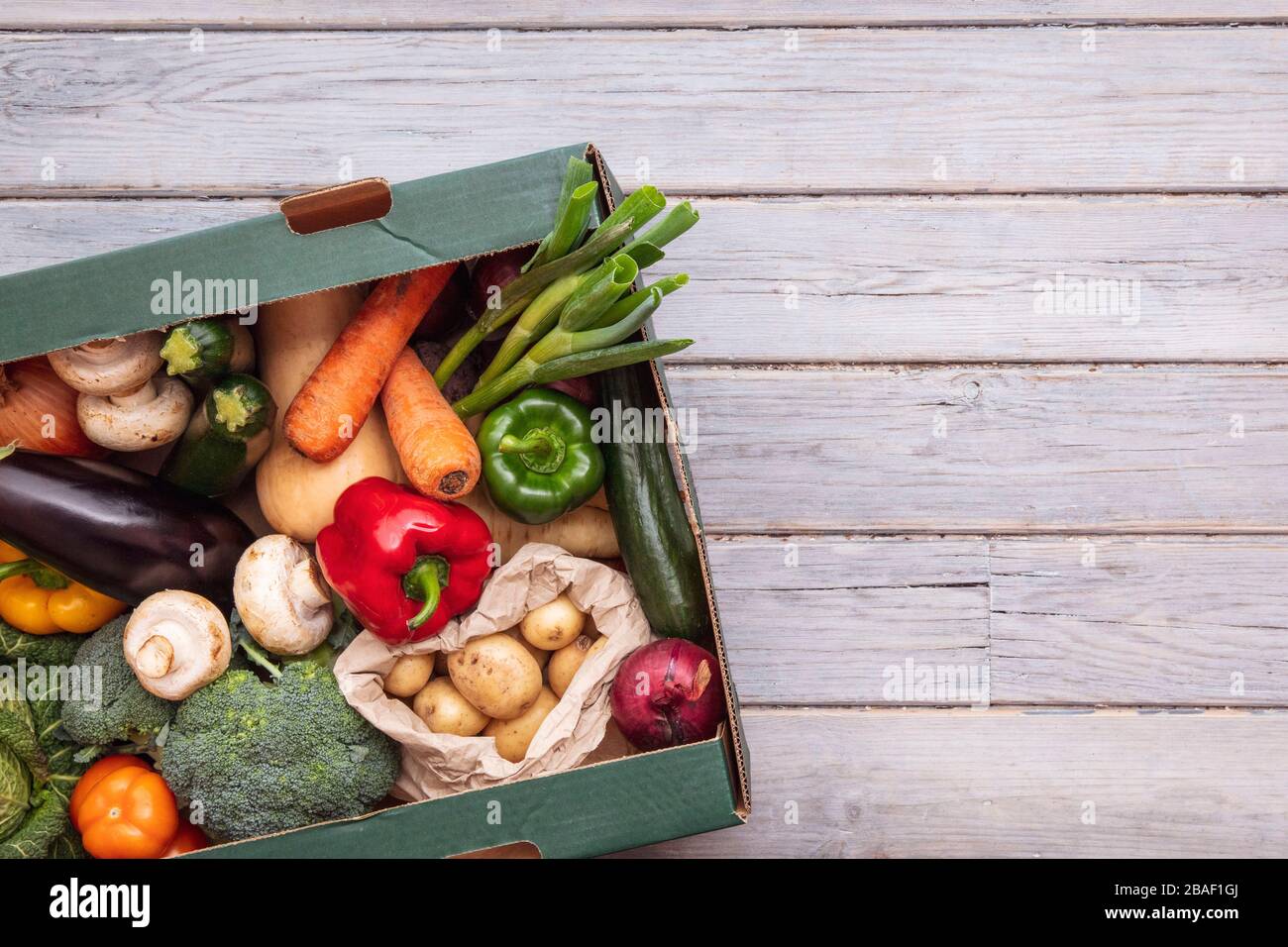 Boîte de livraison de légumes bio frais sur fond de bois Banque D'Images