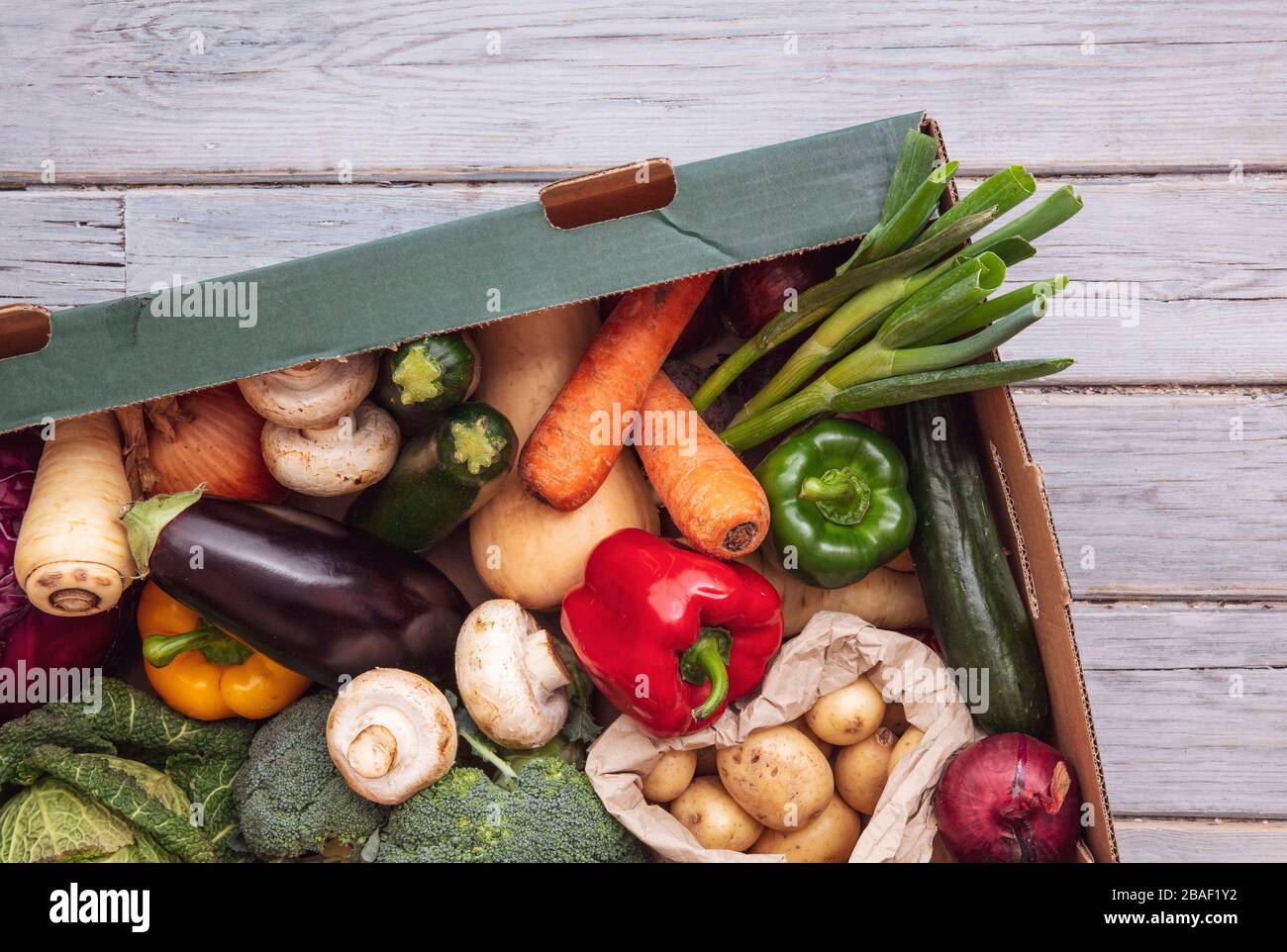Boîte de livraison de légumes bio frais sur fond de bois Banque D'Images