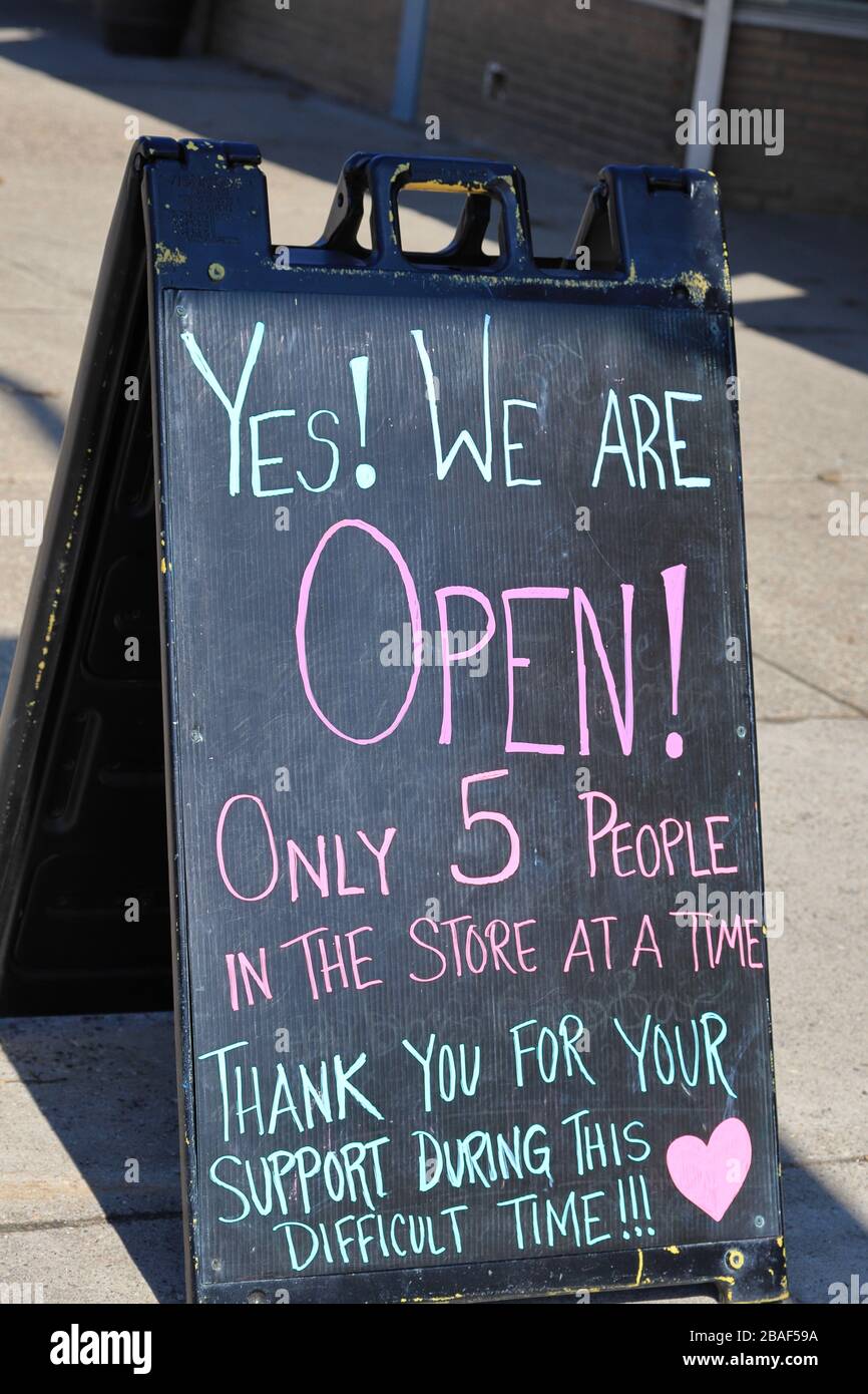 Signe « nous sommes ouverts » lors de la pandémie de COVID-19 montrant des restrictions à l'entrée dans une petite entreprise. Banque D'Images