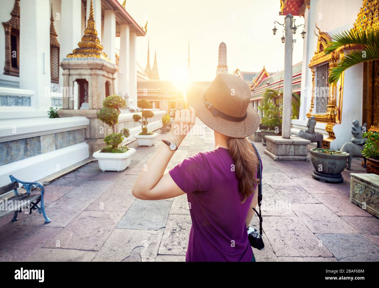 Dans le chapeau femme touristique et violet t-shirt avec une photo dans l'appareil photo au coucher du soleil temple de Wat Pho à Bangkok, Thaïlande Banque D'Images