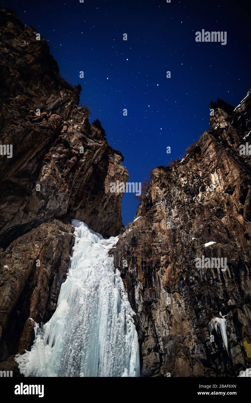 Cascade de glace dans la nuit d'hiver à la montagne ciel étoilé avec grande ourse constellation Banque D'Images