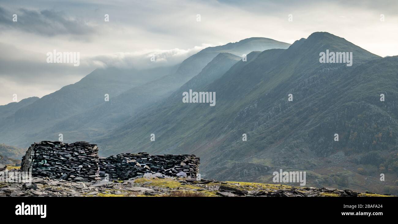 Chalet ruiné dans une carrière d'ardoise gallois contre les montagnes de Snowdonia recouvertes de nuages Banque D'Images