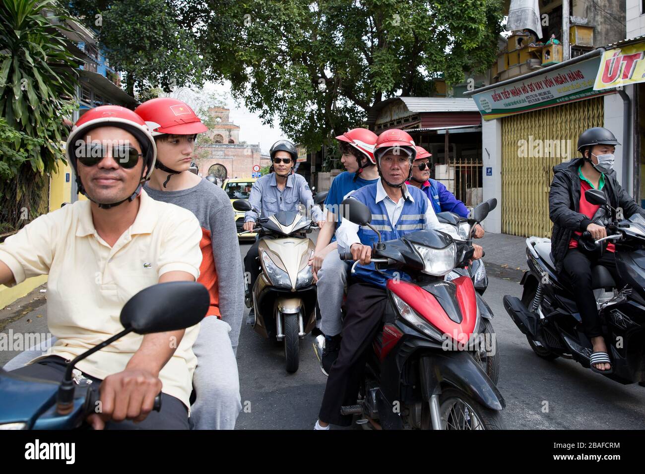 Les touristes étant conduits sur des motos par des Vietnamiens dans les rues de Hue Banque D'Images