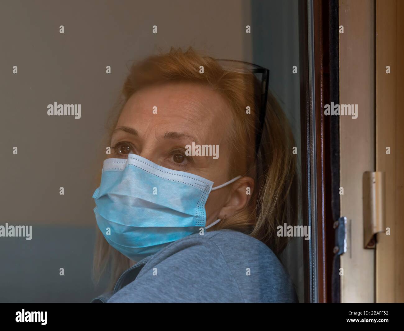 Femme blonde italienne avec masque de protection forcé de rester fermé à la maison pour la quarantaine suite à la propagation du coronavirus Covid-19 Banque D'Images