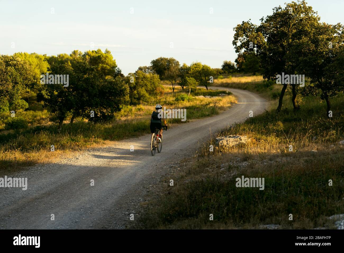 Le cycliste féminin part du travail sur du gravier Banque D'Images