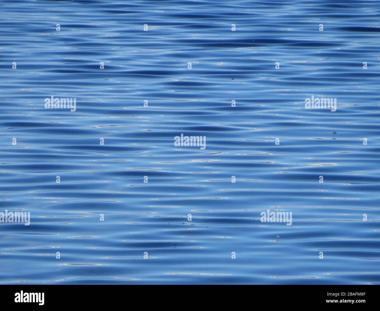 Texture ou structure fond du lac d'eau claire gros plan avec de petites vagues et des reflets légers , en bleu nuit / bleu marine , Islande Banque D'Images