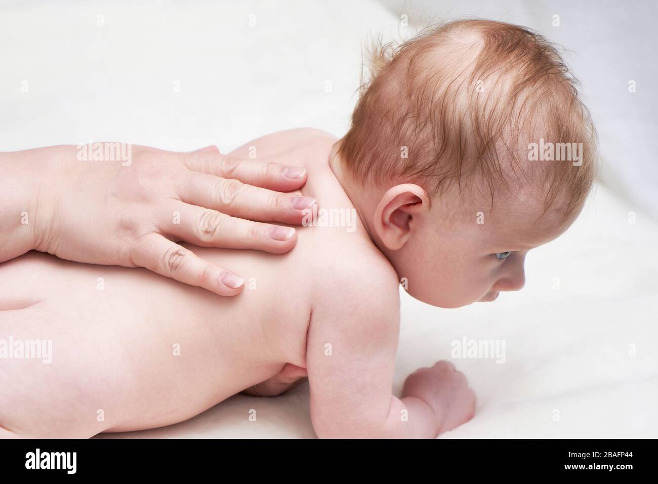 Femme faisant un massage de dos à bébé sur un lit léger gros plan Banque D'Images