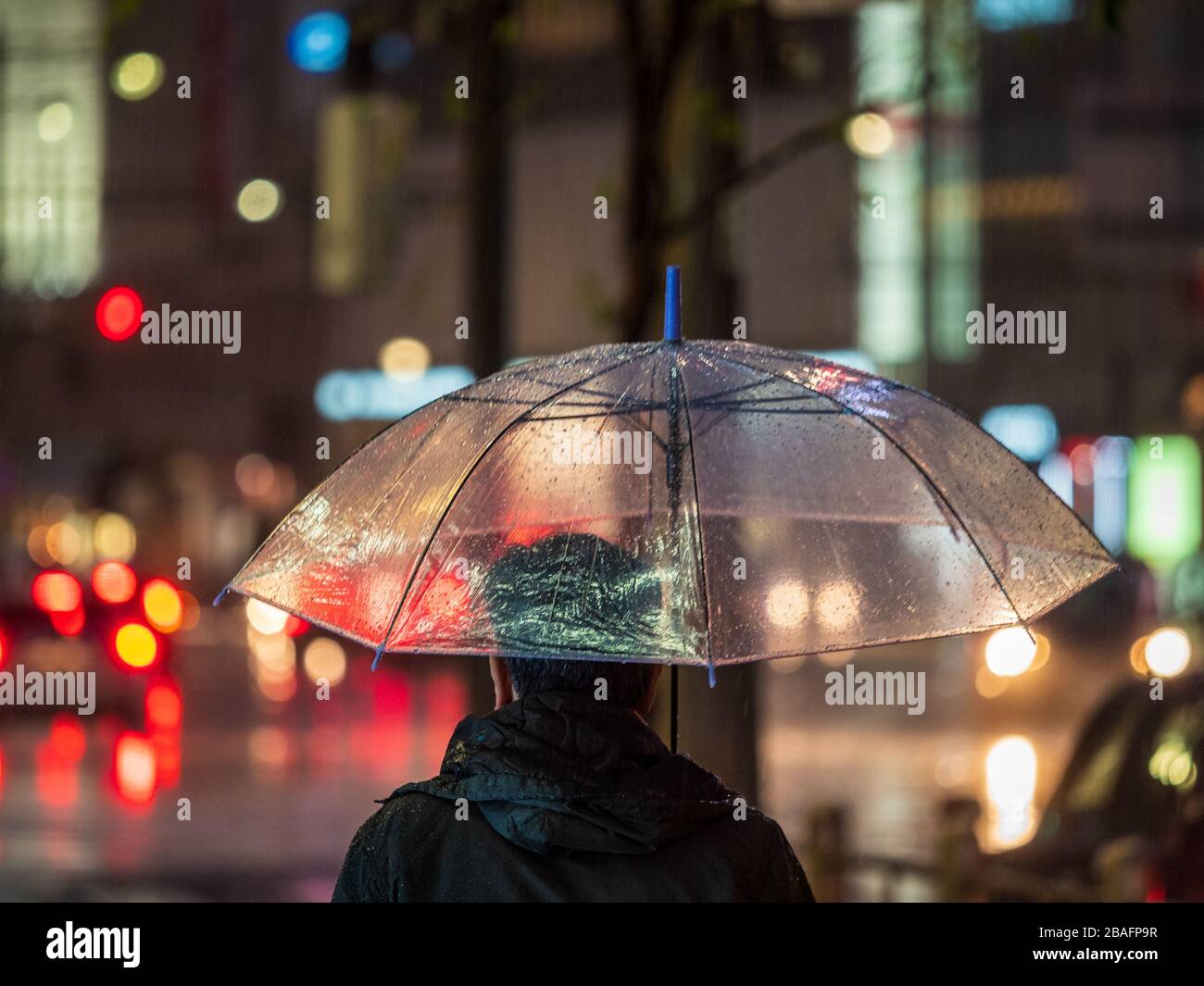 Tokyo dans la pluie - un homme attend à traverser les lumières pendant la pluie à Tokyo au Japon Banque D'Images