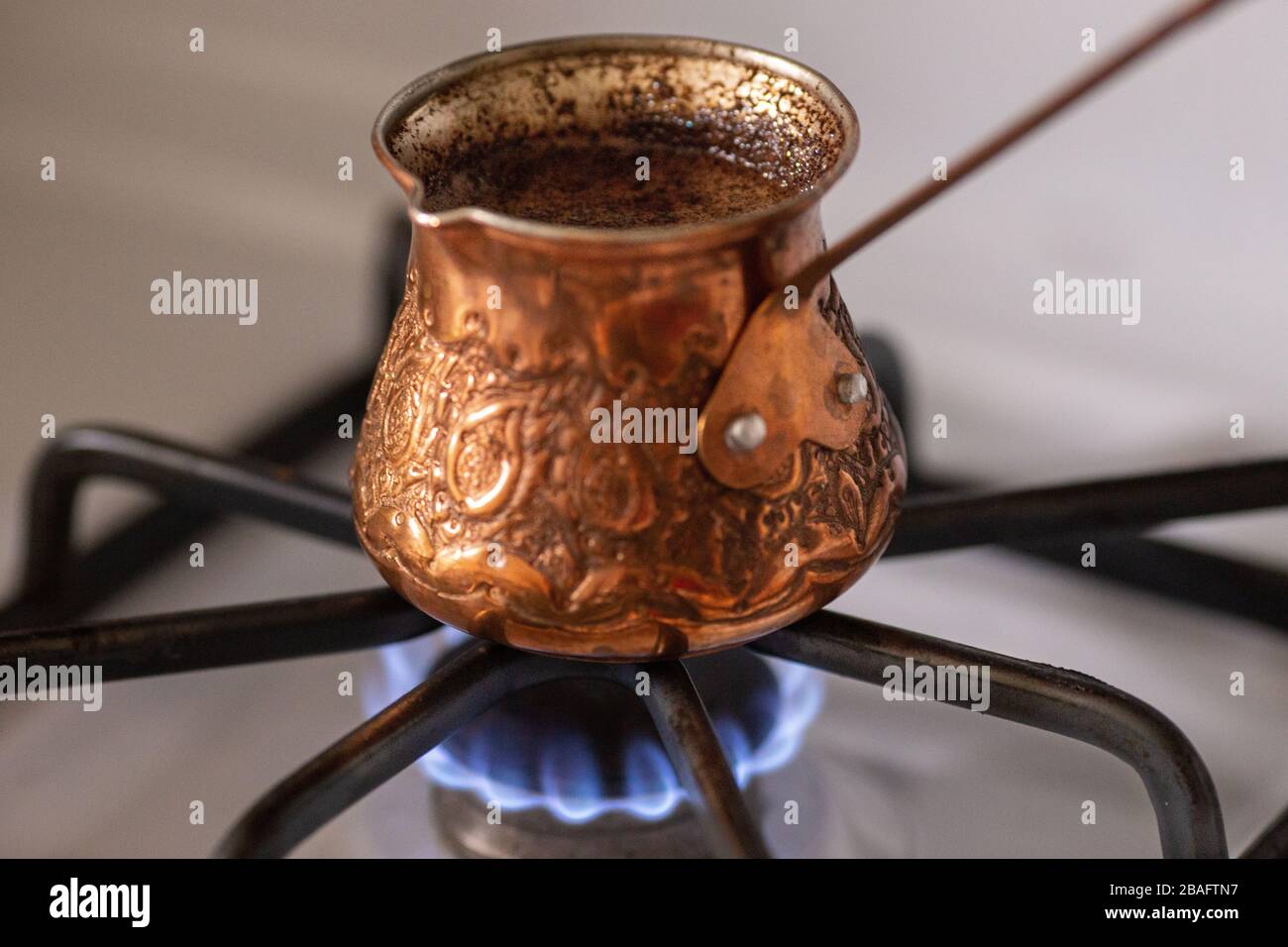 Cafetière turque en cuivre avec un café bouillante à l'intérieur debout sur la cuisinière Banque D'Images