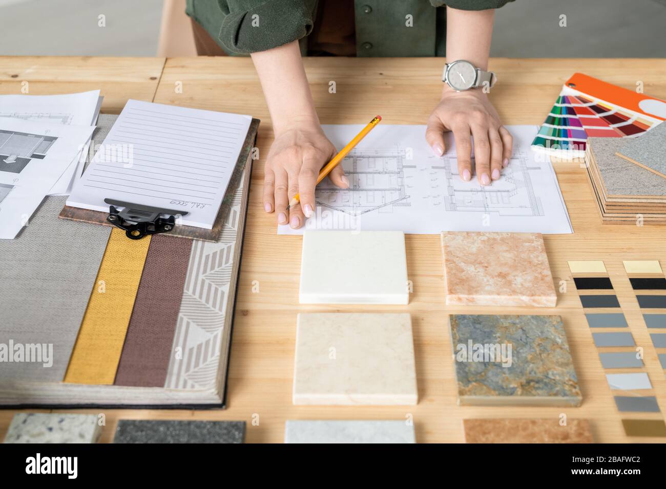 Mains de jeune designer ou architecte créatif féminin avec crayon debout par table en bois tout en travaillant avec des croquis sur papier Banque D'Images