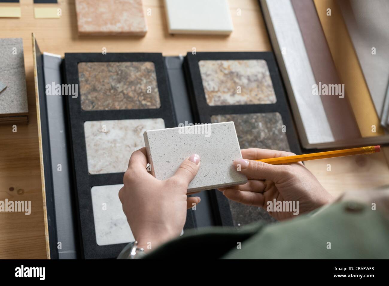 Les mains de jeunes femmes designer tenant un échantillon de panneau sur le lieu de travail tout en apprenant ses caractéristiques et en choisissant un pour la nouvelle commande Banque D'Images