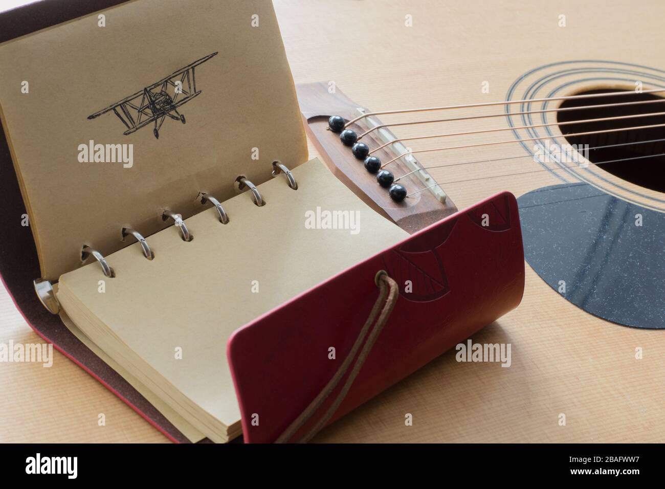 Carnet en cuir avec photo de stylo noir d'un avion sur le fond d'une guitare Banque D'Images
