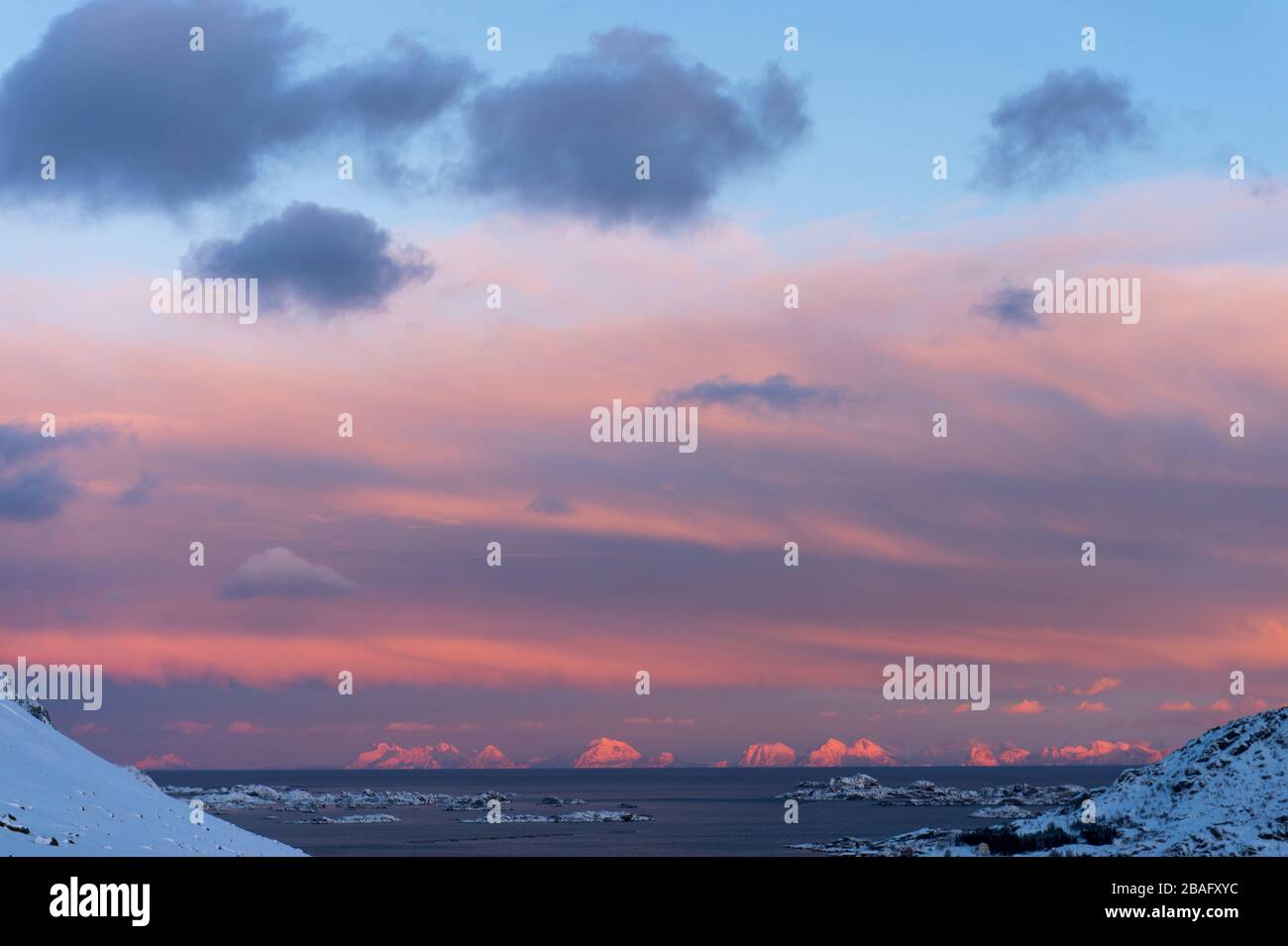 Vue sur les montagnes enneigées au coucher du soleil depuis l'île de Vestvagoy, la deuxième grande île de l'archipel des Lofoten, comté de Nordland, Norvège. Banque D'Images