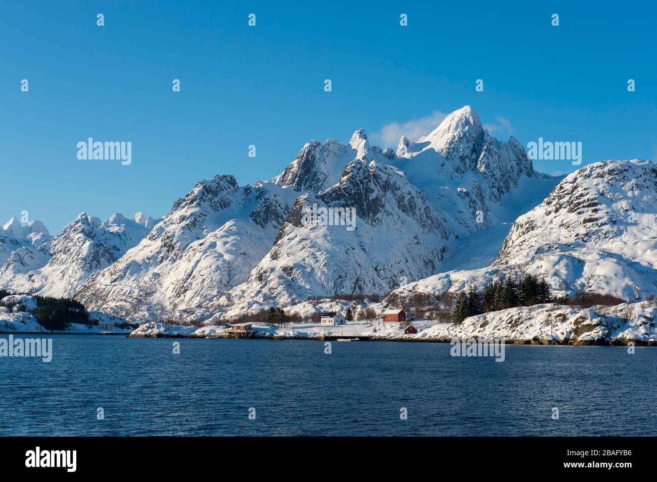 Vue sur les montagnes enneigées et les maisons de l'île d'Austvag près du célèbre Trollfjord dans les îles Lofoten, comté de Nordland, Norvège. Banque D'Images