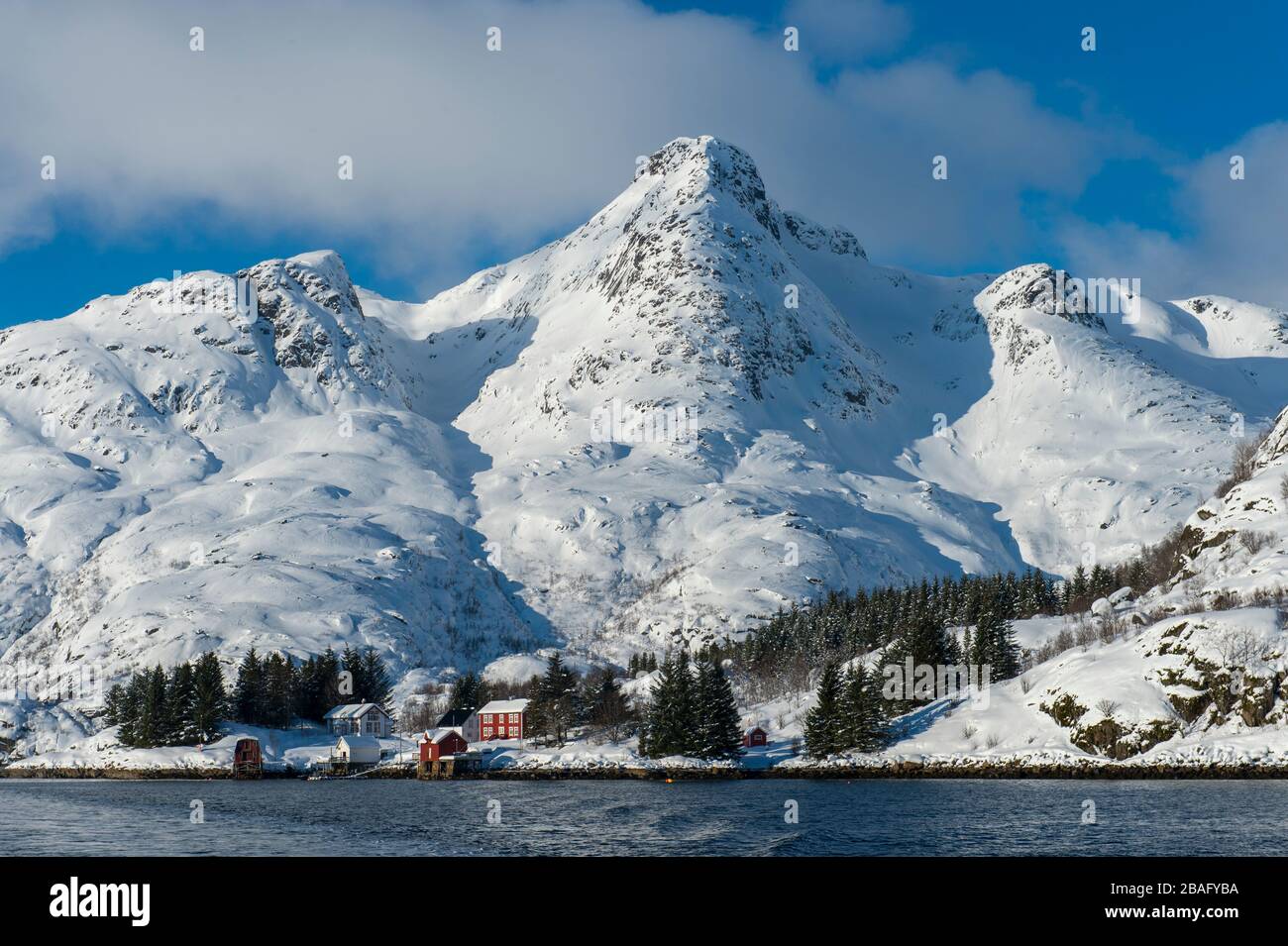 Vue sur les montagnes enneigées et les maisons de l'île d'Austvag près du célèbre Trollfjord dans les îles Lofoten, comté de Nordland, Norvège. Banque D'Images