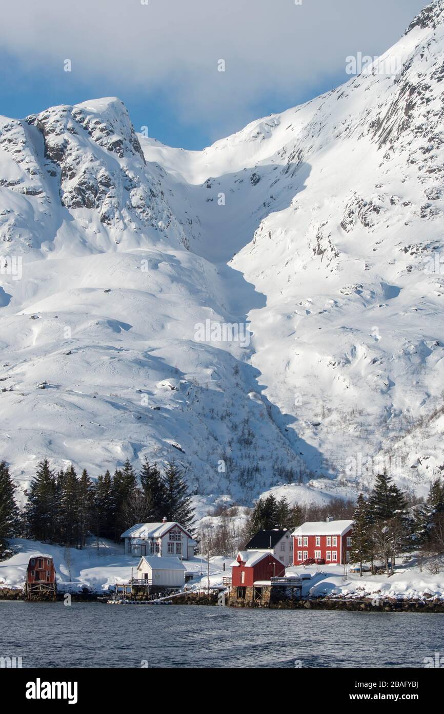 Vue sur les montagnes enneigées et les maisons de l'île d'Austvag près du célèbre Trollfjord dans les îles Lofoten, comté de Nordland, Norvège. Banque D'Images