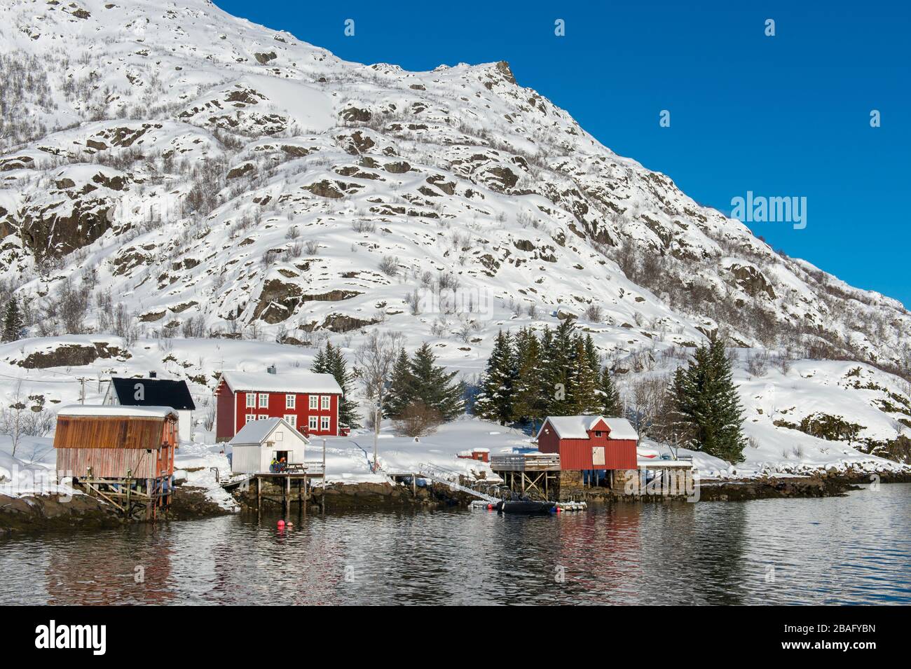 Vue sur les montagnes enneigées et les maisons de l'île d'Austvag près du célèbre Trollfjord dans les îles Lofoten, comté de Nordland, Norvège. Banque D'Images